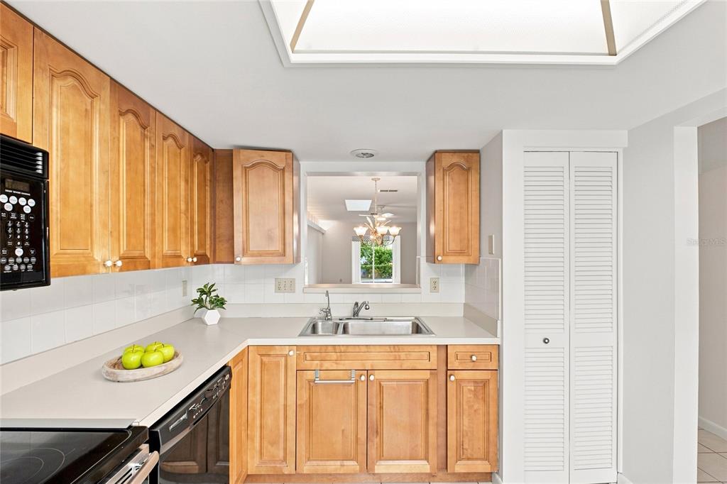 A kitchen features light wood cabinets, a stainless steel sink, and a pass-through window — 3370 STONEHAVEN COURT W UNIT B, PALM HARBOR, FL