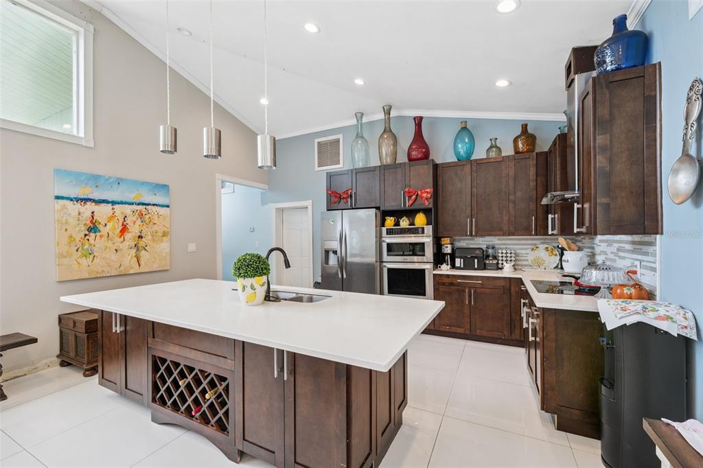 A kitchen features dark wood cabinets, a white quartz island, and a vaulted ceiling — 4527 REDCOAT DRIVE, WESLEY CHAPEL, FL