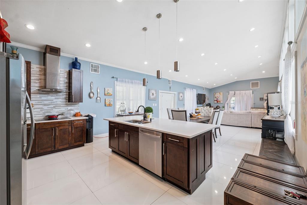 A kitchen with dark wood cabinets, white countertops, and stainless steel appliances in an open-concept room — 4527 REDCOAT DRIVE, WESLEY CHAPEL, FL