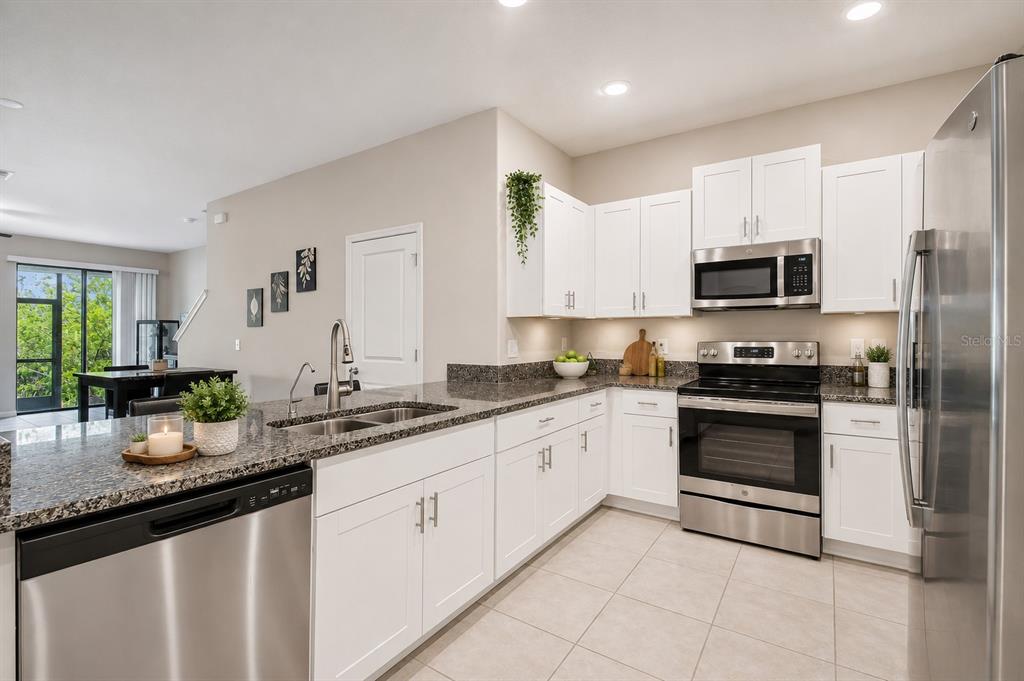 A kitchen with white cabinets, stainless steel appliances, and granite countertops — 633 ROYAL EMPRESS DRIVE, RUSKIN, FL