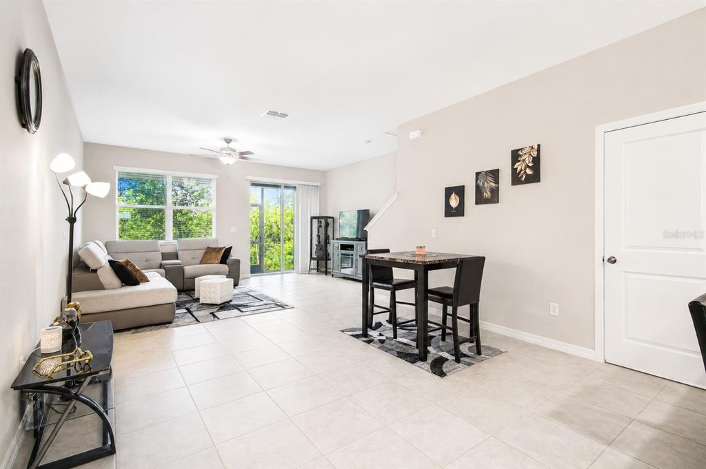 A bright living and dining area with tile floors, a sectional sofa, and sliding doors — 633 ROYAL EMPRESS DRIVE, RUSKIN, FL