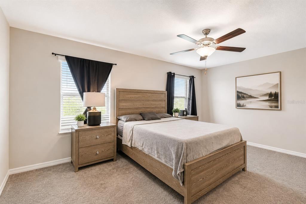 A bedroom features a wooden bed frame, two matching nightstands, and a ceiling fan — 633 ROYAL EMPRESS DRIVE, RUSKIN, FL
