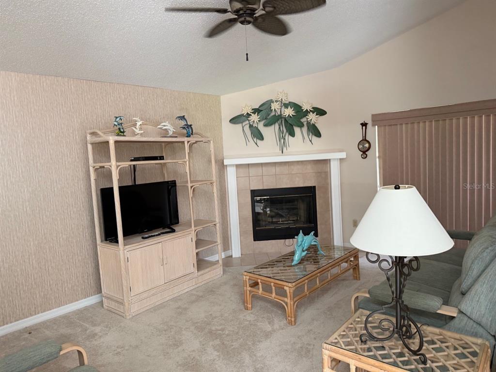 A living room features a fireplace, a television entertainment center, and a glass-topped coffee table — 540 CEDAREDGE DRIVE, NEW SMYRNA BEACH, FL
