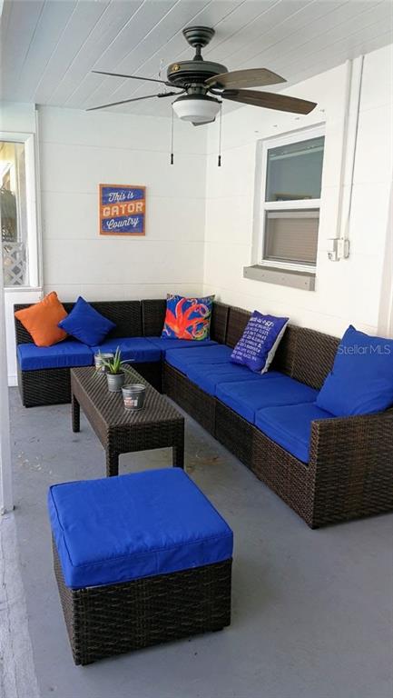 A covered porch features dark wicker sectional seating with blue cushions and a ceiling fan — 2205 59TH STREET S, GULFPORT, FL