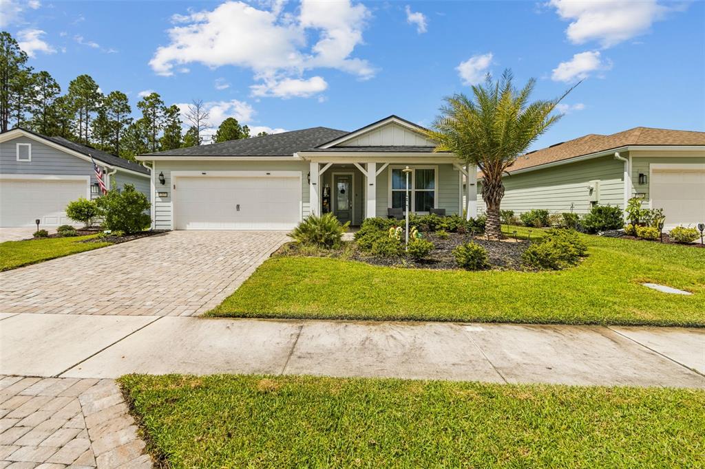 A light green single-story house with a paver driveway and a palm tree in front — 217 ETHEREAL SQUARE, YULEE, FL