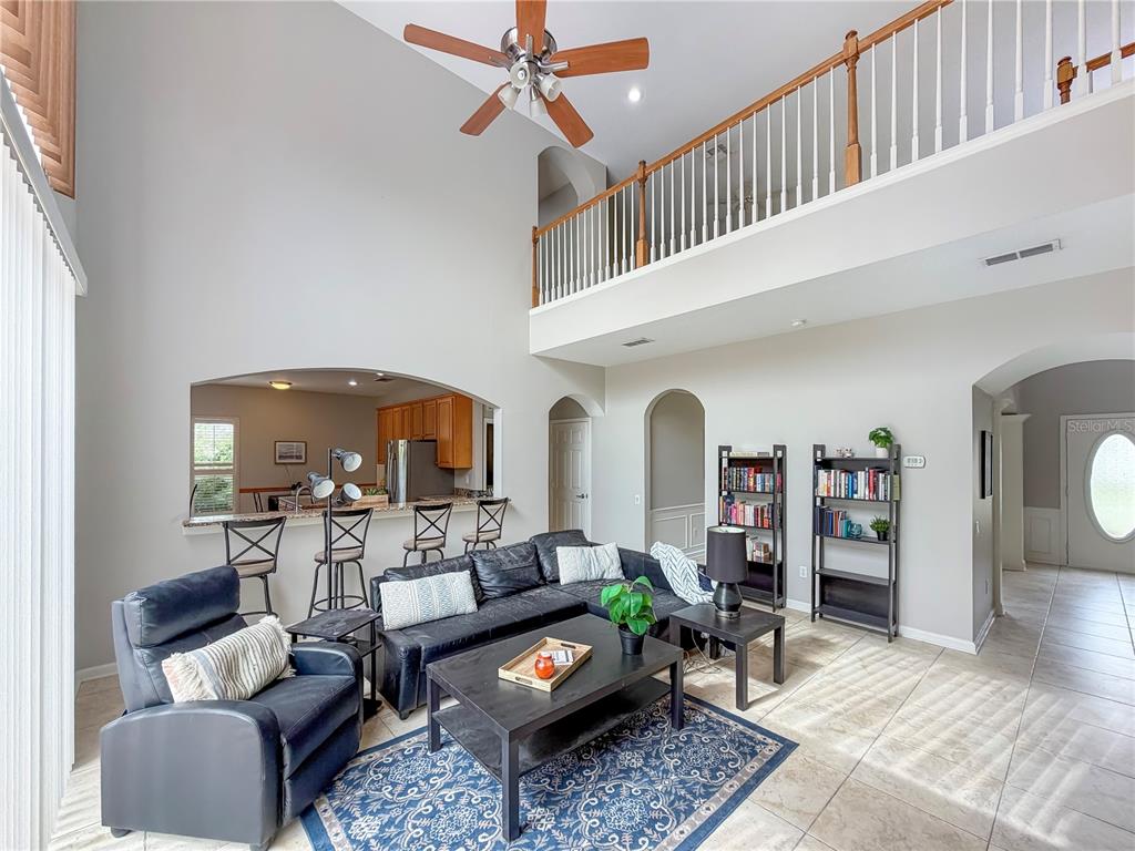 A living room with high ceilings, a loft balcony, and an open kitchen pass-through — 10172 WINDERMERE CHASE BOULEVARD, GOTHA, FL