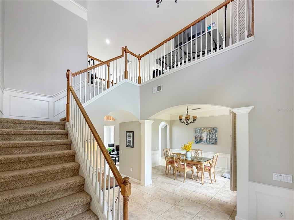 A carpeted staircase leads to a landing overlooking a dining room with tile flooring — 10172 WINDERMERE CHASE BOULEVARD, GOTHA, FL