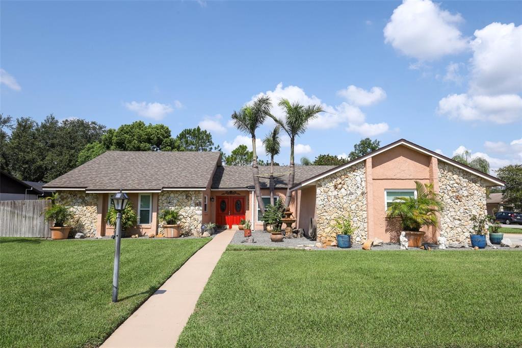 A single-story house with a stone facade, red double doors, and palm trees in front — 1534 PEREZ STREET, ORLANDO, FL
