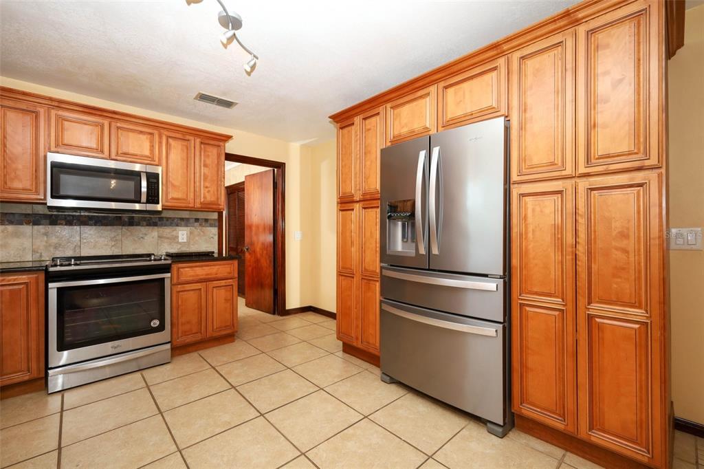 A kitchen with wood cabinets, stainless steel appliances, and tile flooring — 1534 PEREZ STREET, ORLANDO, FL