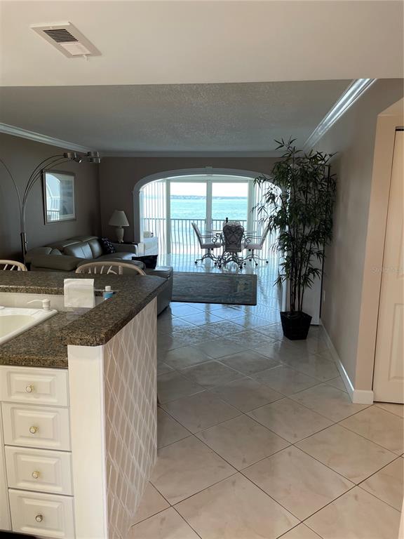 A kitchen island overlooks a living area with tile floors and a view of the water — 895 S GULFVIEW BOULEVARD UNIT 303, CLEARWATER BEACH, FL