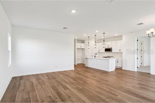 An open-concept kitchen with white cabinetry and a central island overlooks a spacious living area — 3173 SAILHOUSE DRIVE, ST CLOUD, FL