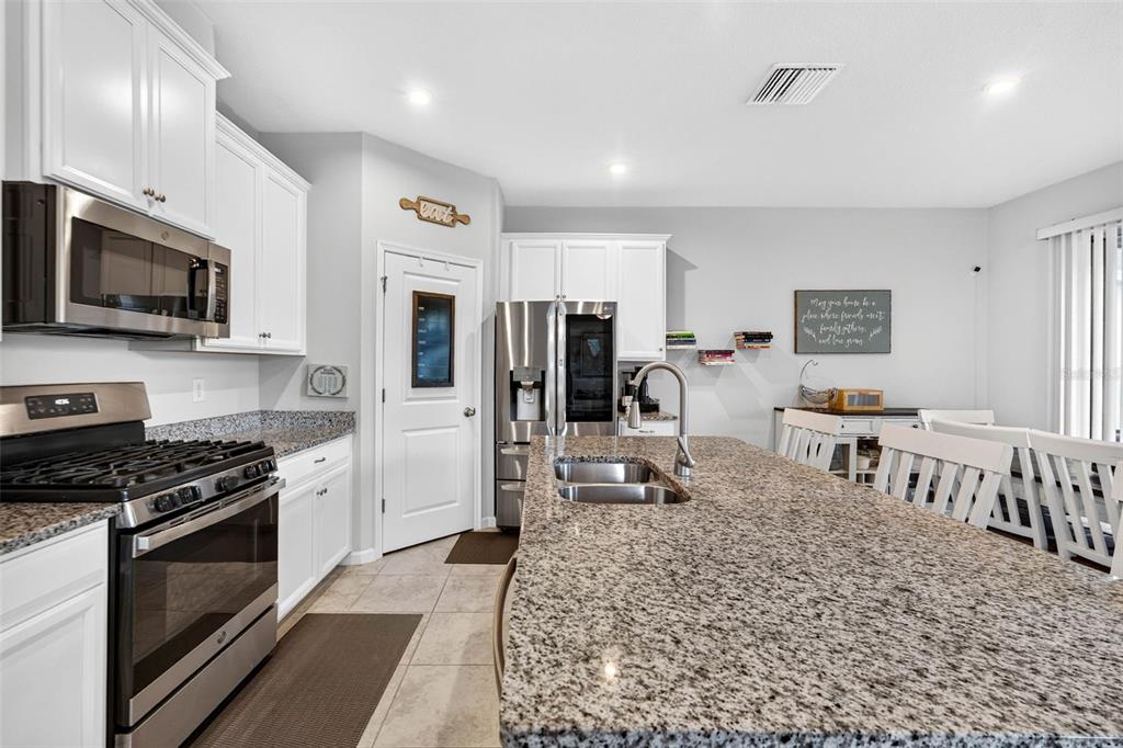 A kitchen features white cabinets, granite countertops, a large island, and stainless steel appliances — 11618 GOLD DUST COURT, RIVERVIEW, FL