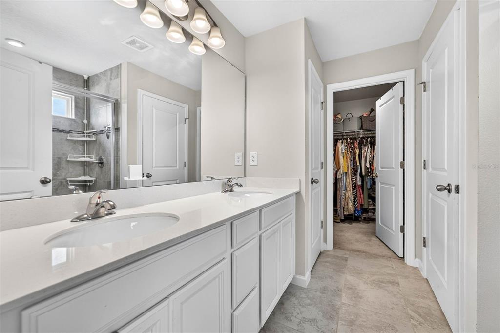 A bathroom features a double vanity with white cabinets, a large mirror, and a walk-in closet — 11618 GOLD DUST COURT, RIVERVIEW, FL
