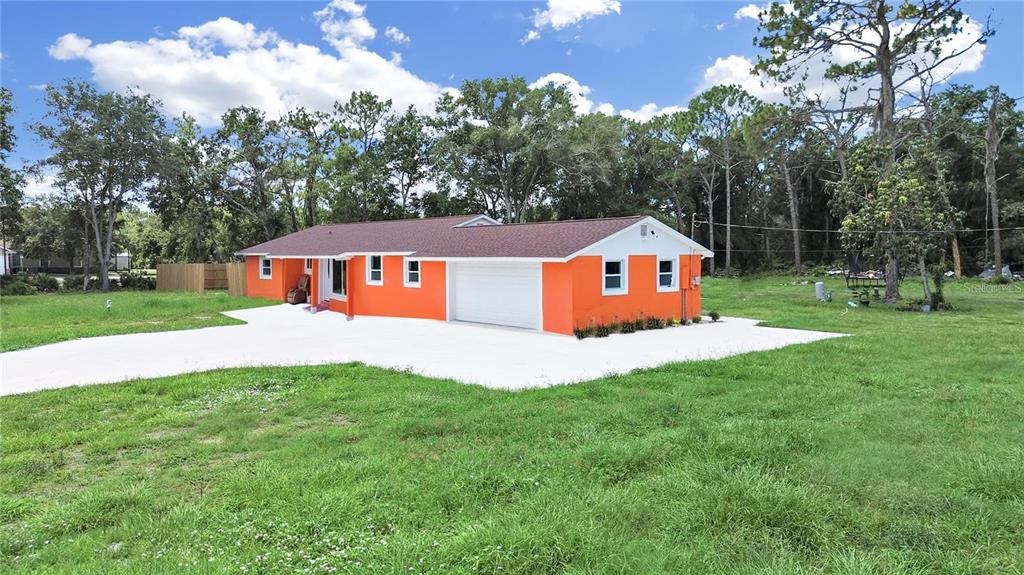 A bright orange single-story house with a white garage door sits on a grassy lot — 1613 33RD STREET SE, RUSKIN, FL