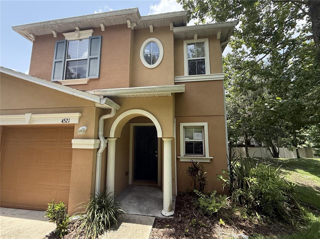A two-story tan stucco house with a garage, arched entryway, and a circular window — 4521 LIMERICK DRIVE, TAMPA, FL