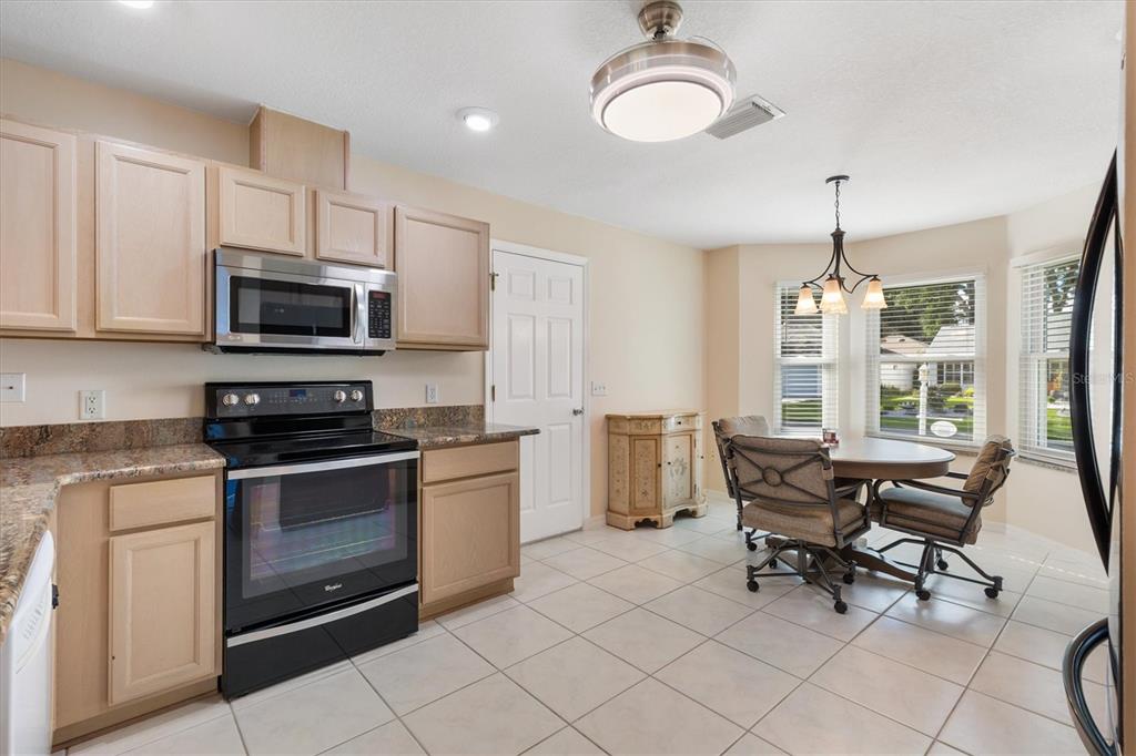 A kitchen with light wood cabinets, stainless steel appliances, and an adjacent dining area — 915 VENTURA DRIVE, LADY LAKE, FL