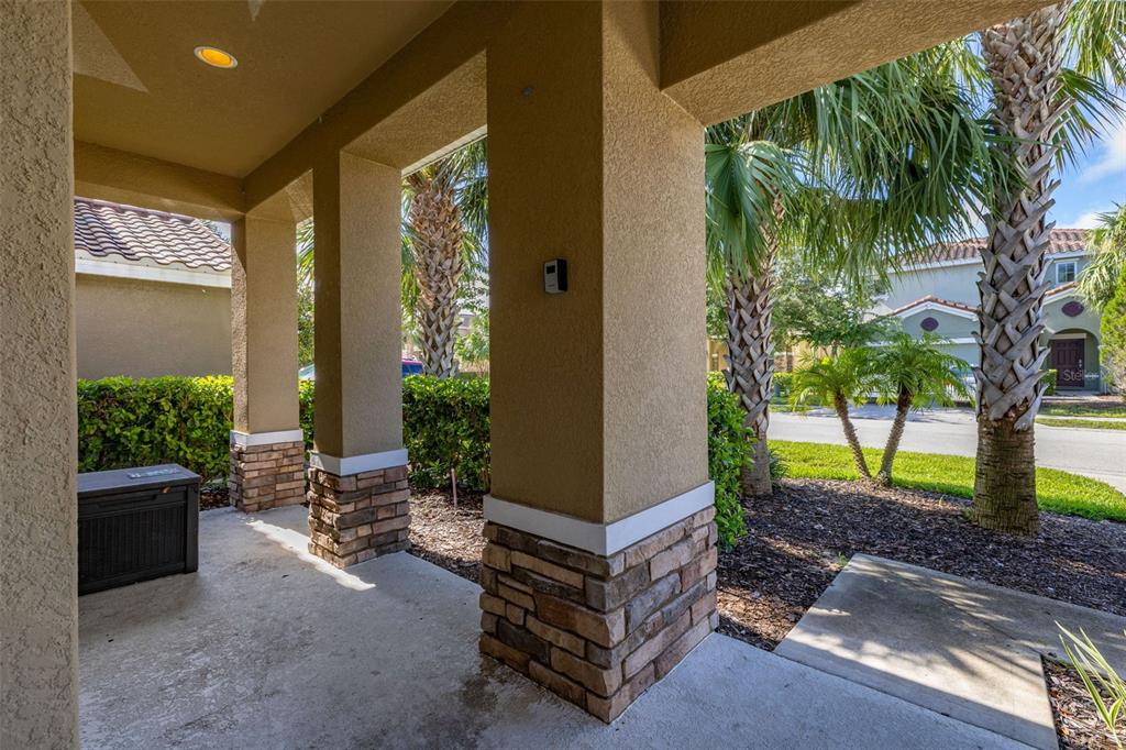 A covered concrete porch features stucco pillars with stone bases and a dark storage bin — 5373 OAKBOURNE AVENUE, DAVENPORT, FL