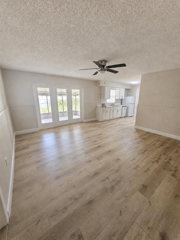 A galley-style kitchen features white cabinets, light wood-look flooring, and stainless steel appliances — 4518 GASPARILLA AVENUE, ORLANDO, FL