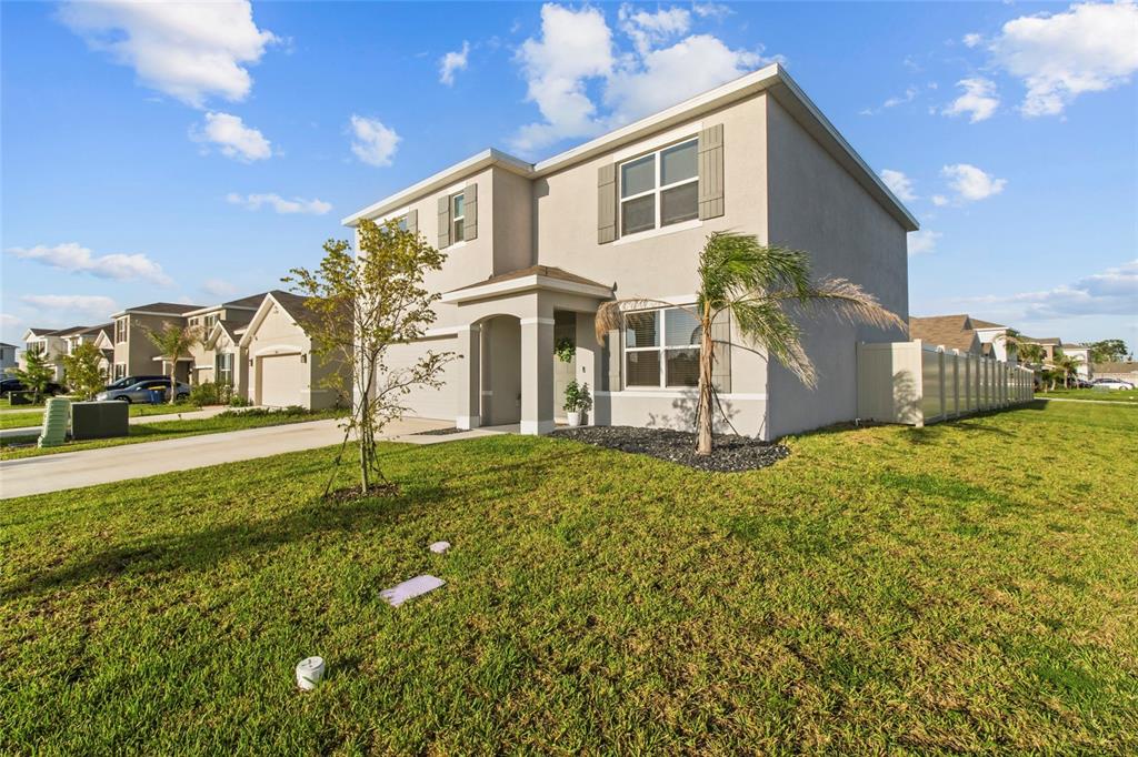 A two-story suburban house with a beige stucco exterior and a small front yard — 8210 DOLPHIN BLUFF BOULEVARD, WESLEY CHAPEL, FL
