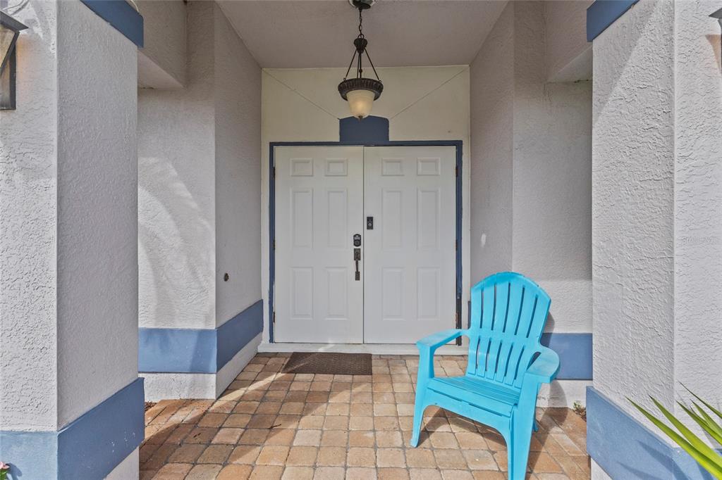 A bright blue Adirondack chair sits on a paved porch in front of double doors — 2373 AMNESTY DRIVE, NORTH PORT, FL