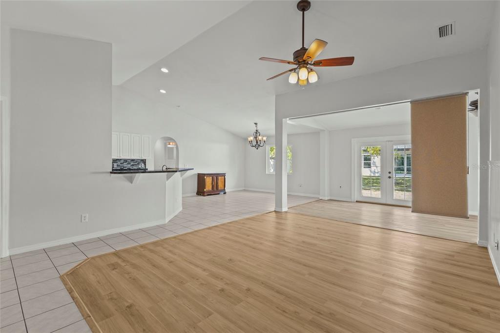 An open-concept living area features light wood flooring, tile transitions, and a ceiling fan — 2373 AMNESTY DRIVE, NORTH PORT, FL