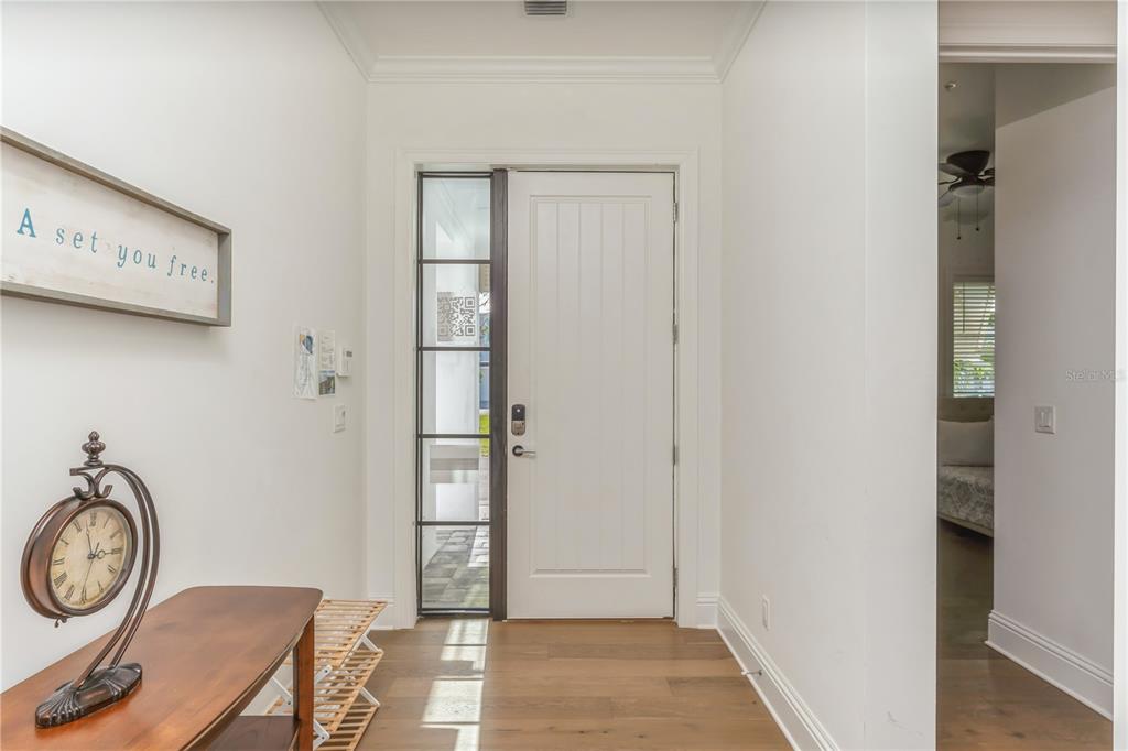 An entryway features a white door with a side window, wood flooring, and a wall clock — 119 OCEAN ESTATES DRIVE, HUTCHINSON ISLAND, FL