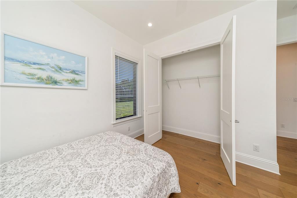 A bedroom features light wood flooring, a white closet, a window with blinds, and wall art — 119 OCEAN ESTATES DRIVE, HUTCHINSON ISLAND, FL