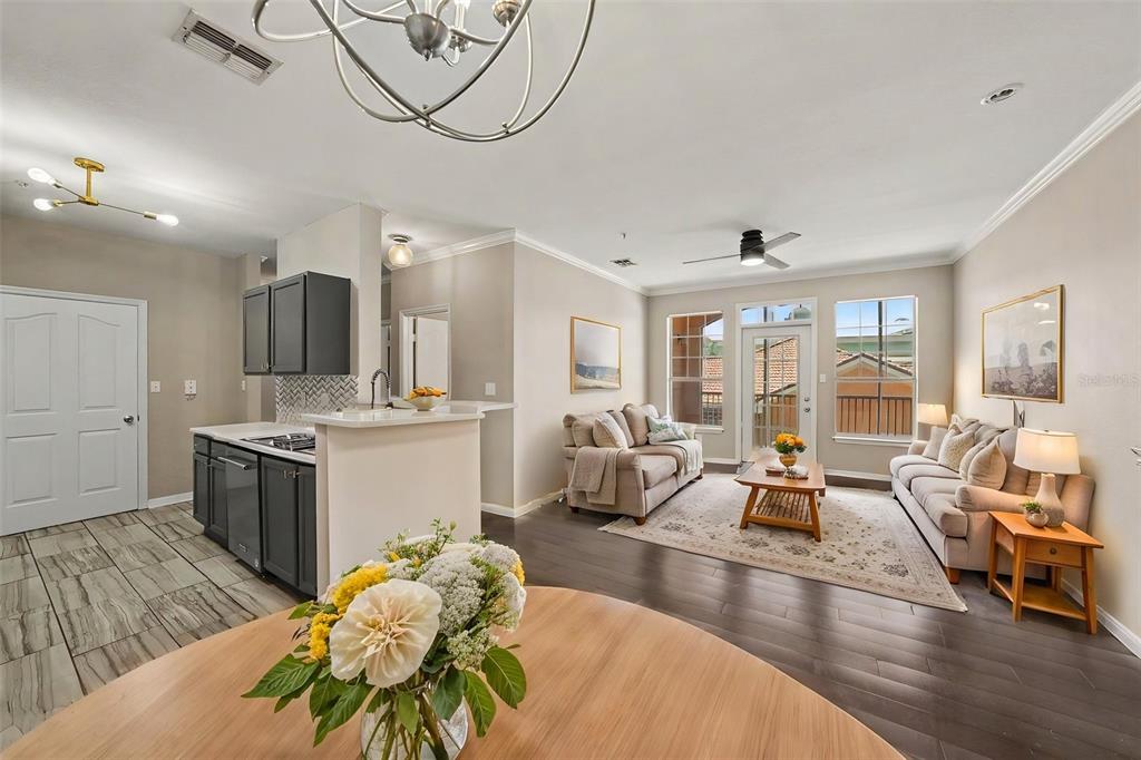 An open-concept living and dining area features wood flooring, a round table, and neutral furniture — 5000 CULBREATH KEY WAY UNIT 4203, TAMPA, FL