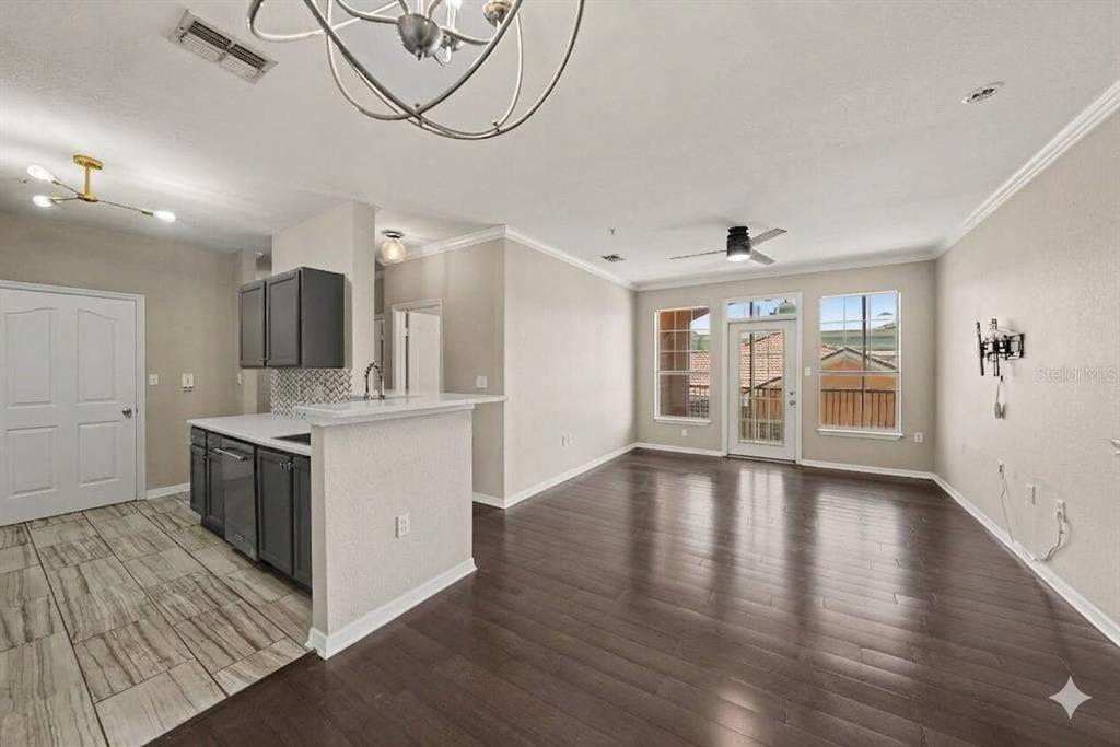 An open-concept living and kitchen area features dark wood flooring, gray cabinets, and a chandelier — 5000 CULBREATH KEY WAY UNIT 4203, TAMPA, FL