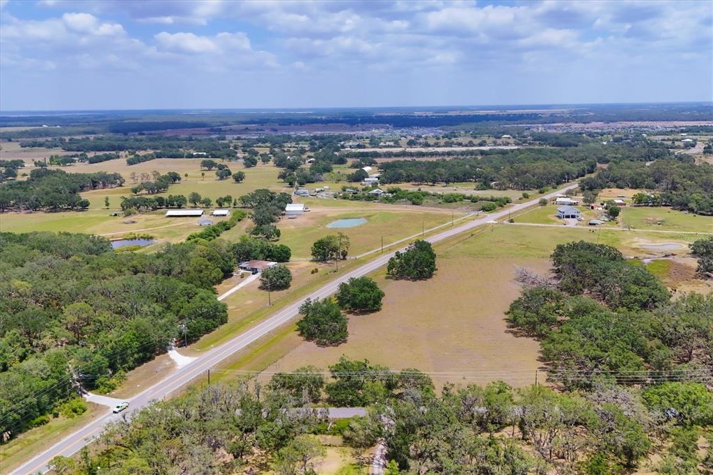 An aerial view shows a rural landscape with a road, scattered trees, and several buildings — 6720 JIM DAVIS ROAD, PARRISH, FL