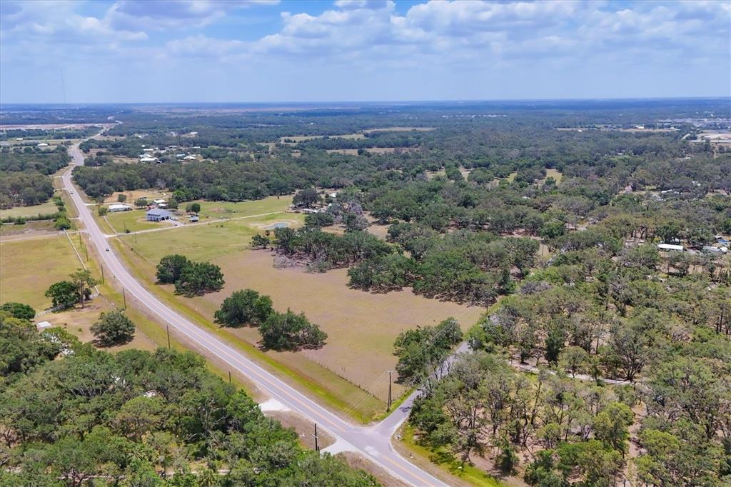 An aerial view shows a rural landscape with a paved road, open fields, and trees — 6720 JIM DAVIS ROAD, PARRISH, FL