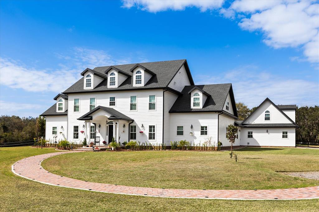A large swimming pool sits on a patio in front of a white house at sunset — 4510 PACKARD AVENUE, ST CLOUD, FL