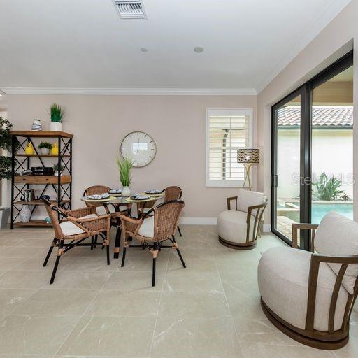 A dining area with a round table, wicker chairs, and a beige armchair near sliding doors — 930 E VENICE AVENUE, VENICE, FL