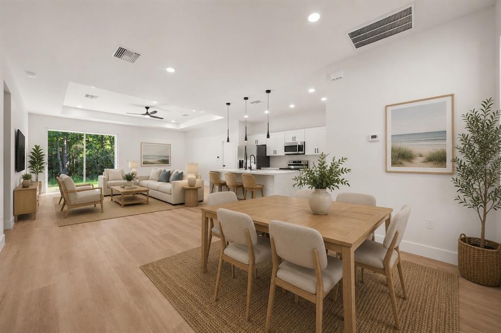 An open-concept living and dining area features light wood flooring, white cabinetry, and large windows — 8636 SUN N LAKE BOULEVARD, SEBRING, FL