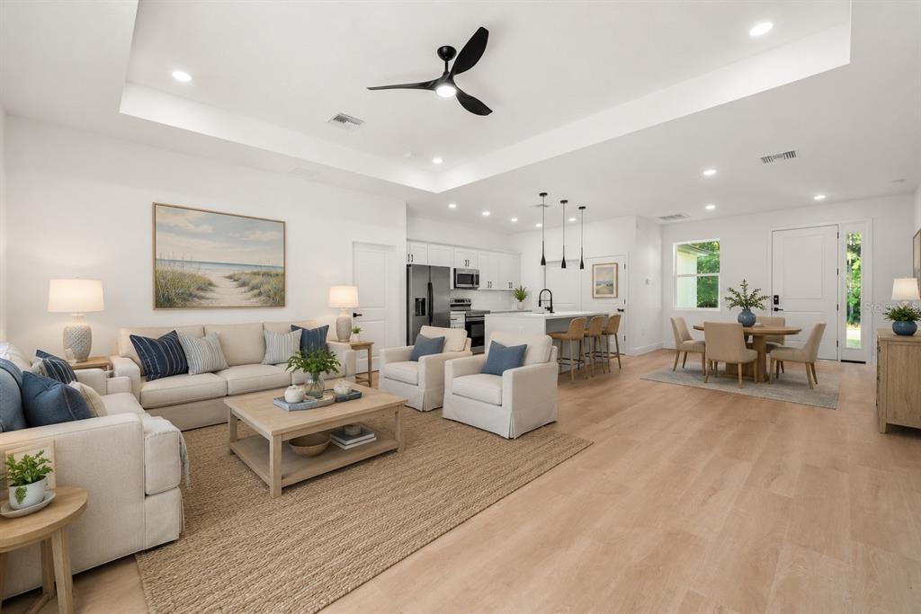 An open-concept living room and kitchen with light wood floors, white cabinetry, and neutral furniture — 8636 SUN N LAKE BOULEVARD, SEBRING, FL