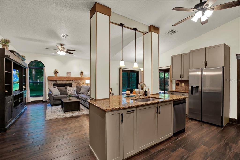 A kitchen island with a sink sits in front of an open-concept living room — 18671 AUTUMN LAKE AVENUE, HUDSON, FL