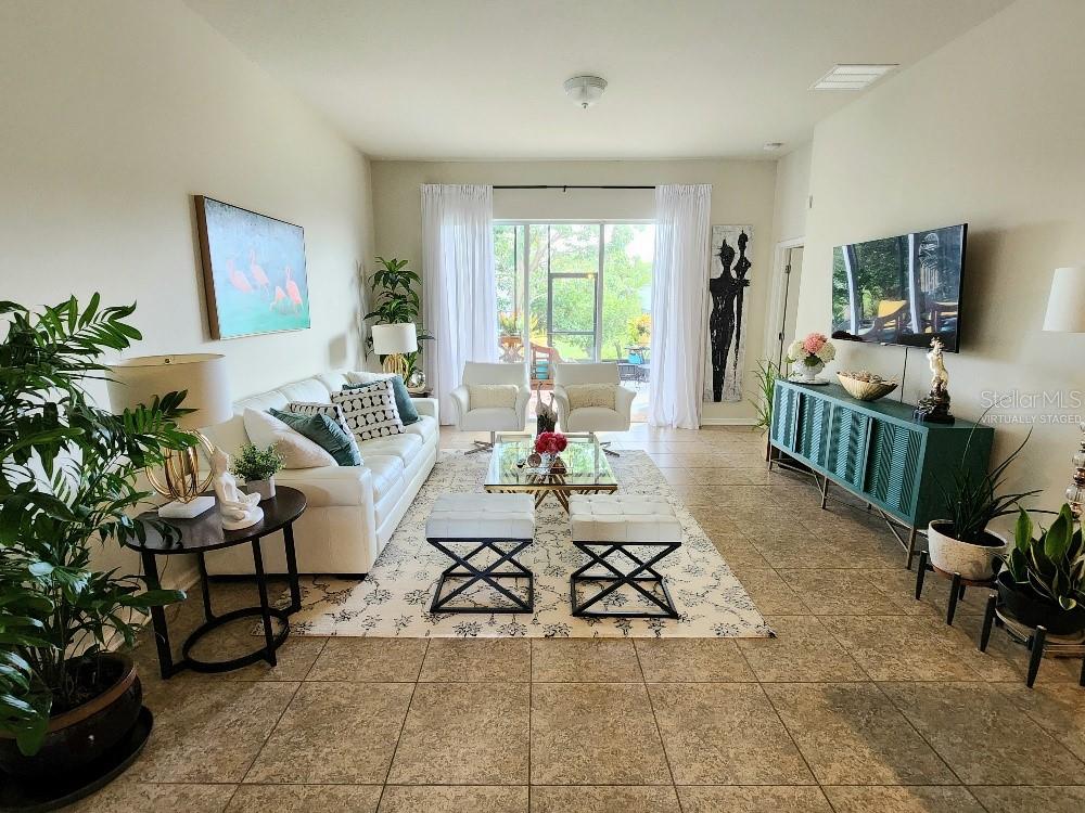 This living room features tile flooring, a white sofa, a glass coffee table, and a television — 9820 50TH STREET CIRCLE E, PARRISH, FL
