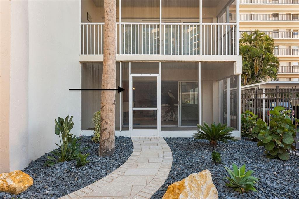 A ground-level patio with a screen door and white railing sits behind a stone path — 800 BENJAMIN FRANKLIN DRIVE UNIT 110, SARASOTA, FL