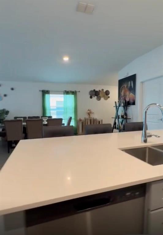 A kitchen island with a white countertop and stainless steel sink overlooks a dining area — 1946 POND PINE COURT, HAINES CITY, FL