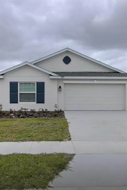 A single-story house with a white stucco exterior, dark blue shutters, and a two-car garage — 1946 POND PINE COURT, HAINES CITY, FL