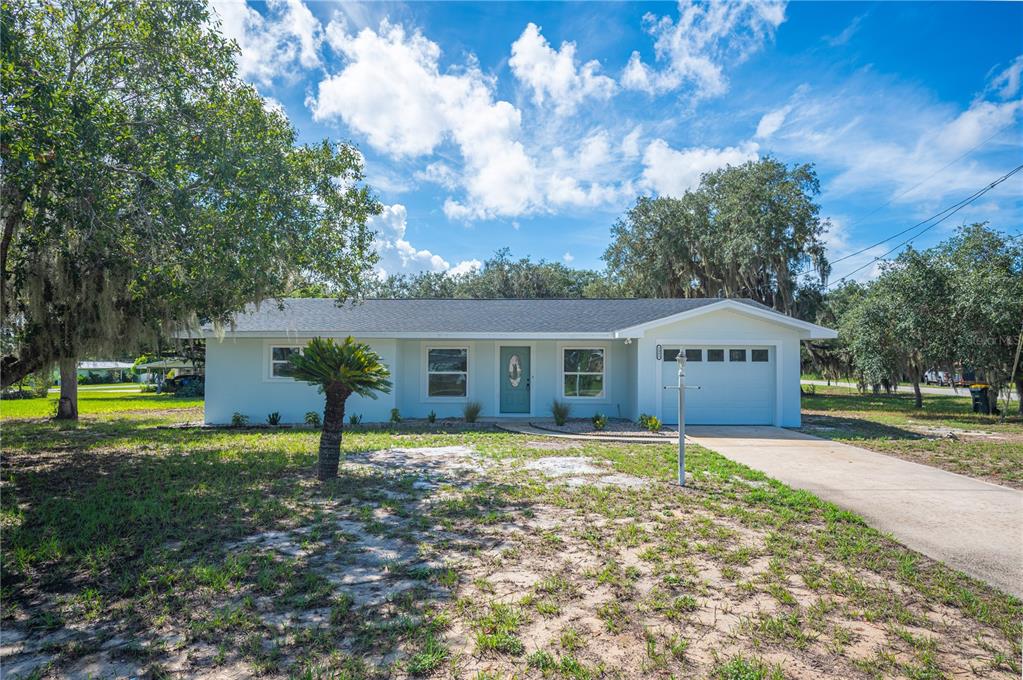 A single-story house with a light blue exterior, a front door, and an attached garage — 2995 W LAKE CHILTON DRIVE, AVON PARK, FL
