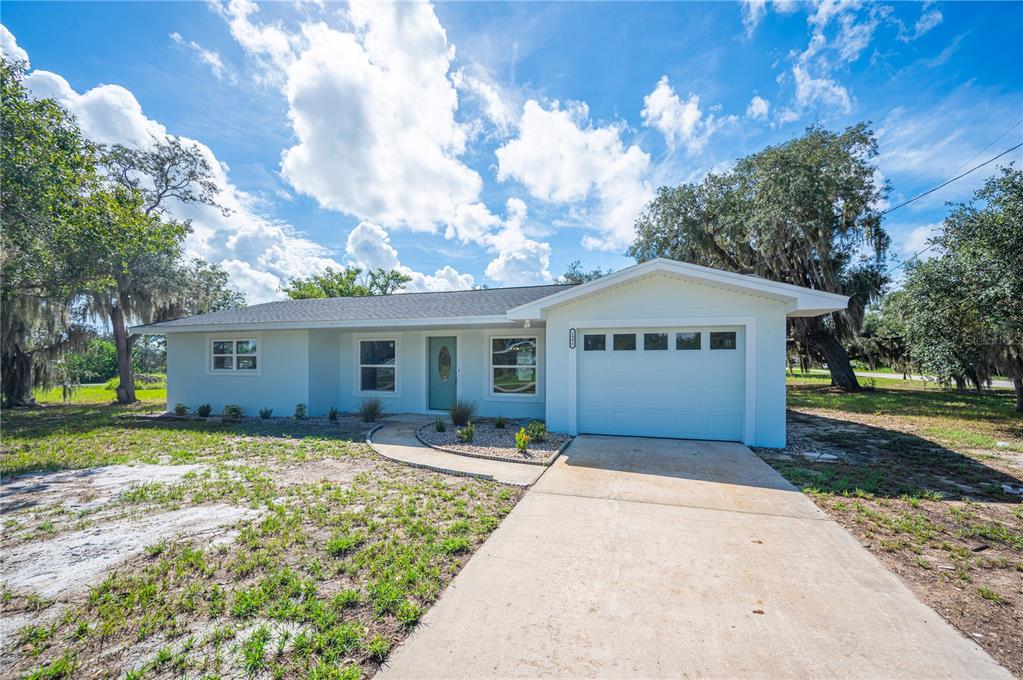 A single-story house with light blue exterior walls, a white garage door, and a concrete driveway — 2995 W LAKE CHILTON DRIVE, AVON PARK, FL
