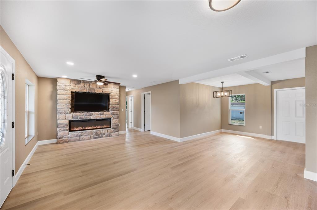 A living room with light wood floors, a stone fireplace, and a dining area — 2995 W LAKE CHILTON DRIVE, AVON PARK, FL