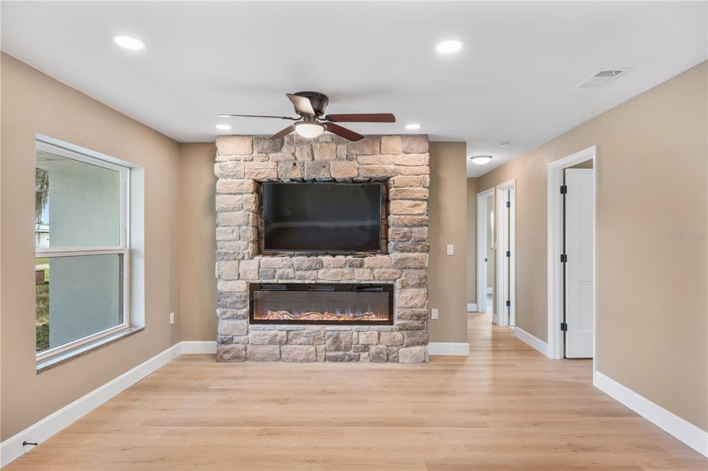 A living room features light wood flooring, a stone fireplace with a television, and recessed lighting — 2995 W LAKE CHILTON DRIVE, AVON PARK, FL