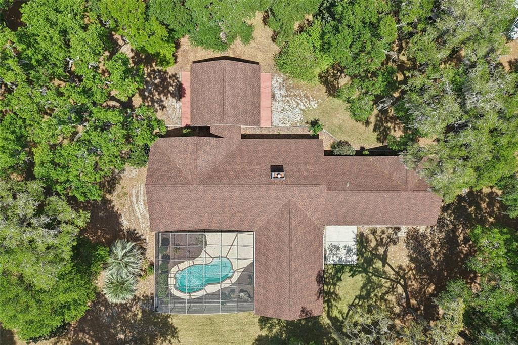 An aerial view shows a house with a brown shingled roof and a screened-in pool — 2685 CR 564, BUSHNELL, FL