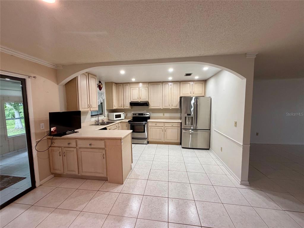 A kitchen with light wood cabinets, stainless steel appliances, and light-colored tile flooring — 3010 YULE TREE DRIVE, EDGEWATER, FL