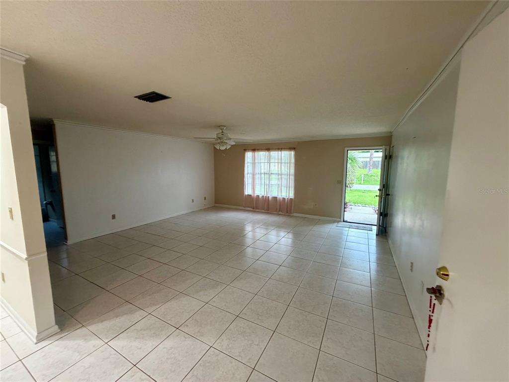 A spacious living room features light-colored floor tiles, a ceiling fan, and an open doorway — 3010 YULE TREE DRIVE, EDGEWATER, FL