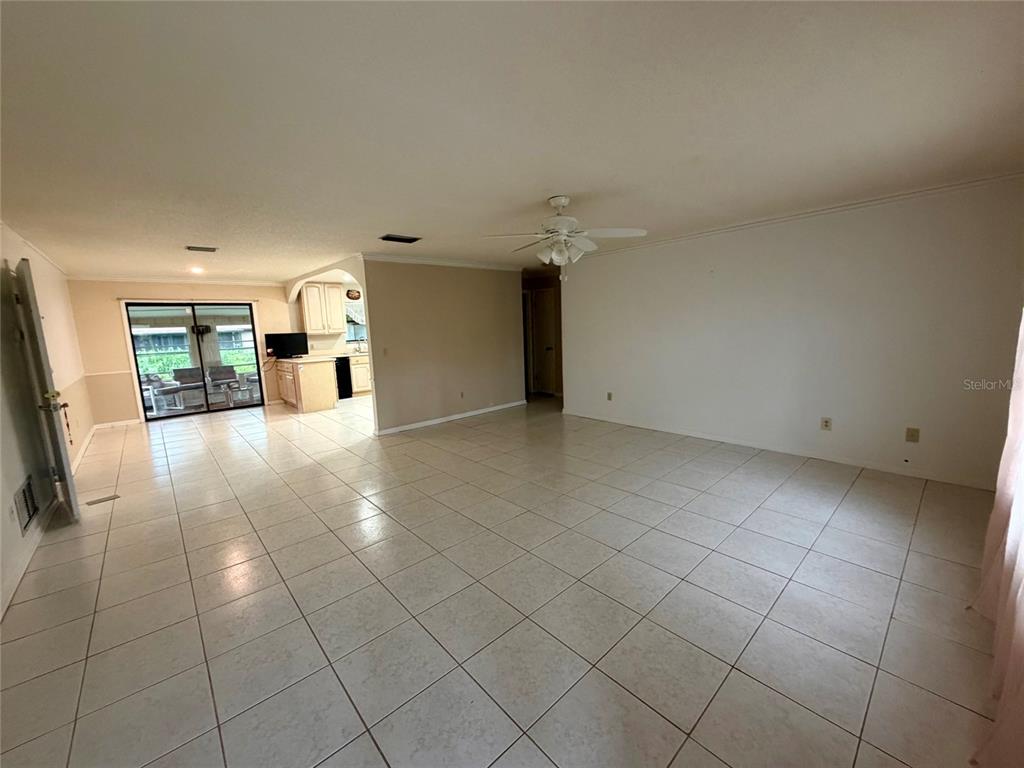 A spacious living room with light tile flooring, a ceiling fan, and an adjacent kitchen — 3010 YULE TREE DRIVE, EDGEWATER, FL