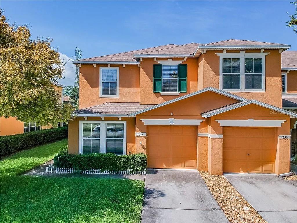 A two-story orange stucco house features two garage doors and green window shutters — 2048 SUN DOWN DRIVE, CLEARWATER, FL