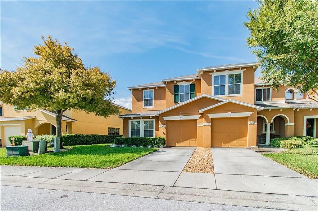A two-story tan townhouse features two garage doors and a front lawn with trees — 2048 SUN DOWN DRIVE, CLEARWATER, FL